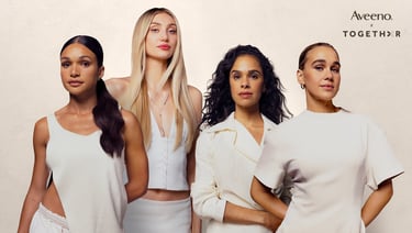 Four diverse women posing in white outfits for an Aveeno skin care campaign brand collaboration.