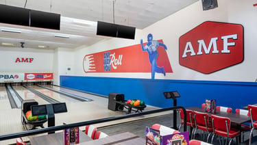 A clean interior view of an AMF bowling alley with modern lanes, ball returns, and seating areas.