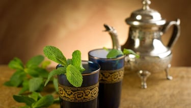 Théière avec verres à thé et brins de menthe dans le rituel traditionnel marocain