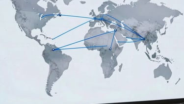 A wide-angle photograph of a modern North American / Global Turkish office. A large digital screen in the background shows a world map with Soft Steel Blue connection lines between New Mexico, Japan, and the UAE. The atmosphere is professional and global.