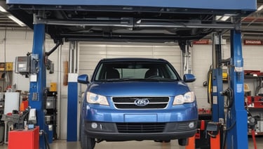 A small automotive repair shop with a distinctive red and white facade, located on a quiet street. The building is one story with large glass windows and a sign displaying the name of the business. A black car is parked in front of one of the garage doors. Tree-lined streets with houses are visible in the background, bathed in the soft light of late afternoon.