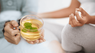 blended image of a woman holding a glass of tea and a glass of tea another woman meditating