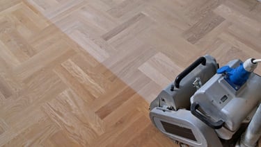 Flooring belt sander sanding hardwood flooring. Professional dustless sanding of hardwood floors in Redmond condo