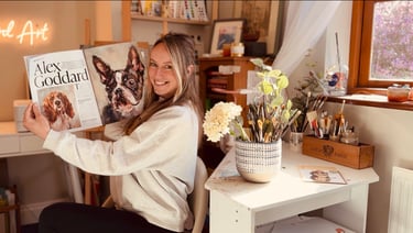 Alex Goddard in her studio with the magazine feature that she was featured in