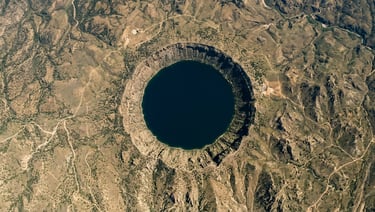 Aerial photograph of a perfectly circular lake filling an ancient confirmed crater, shot from directly above