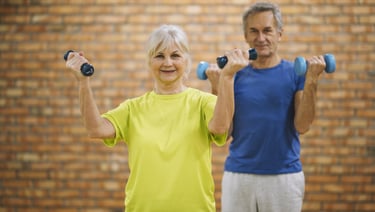 Active senior man and woman doing bicep curls with dumbbells during a fitness class.