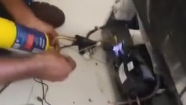 mão do técnico fazendo solda pra conserto de geladeira