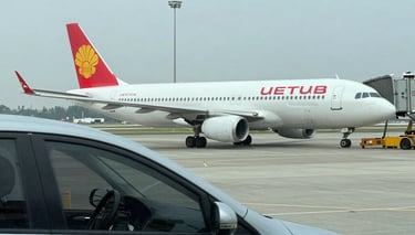 A sleek black sedan waiting outside an airport terminal with luggage nearby.