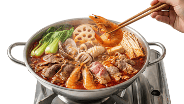 Close-up of a steaming red mala hotpot broth filled with chili peppers and traditional Sichuan spices.