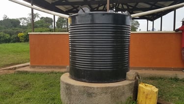 a black plastic water tank sitting on top of a cement block