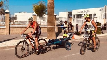 Cyclist in a triathlon race pulling a child in a special needs bike trailer during a marathon event.