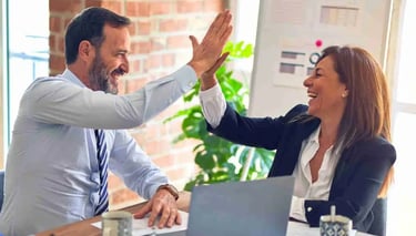 En mentor och en klient gör high five för ett framgångsrik mentorskap som skapat framgång för klienten..