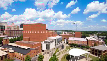 Aerial view of a university campus with brick buildings and an outdoor amphitheater stage. Downtown 