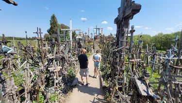 Guide Simas walking with tourists through the Hill of Crosses pilgrimage site in Lithuania .