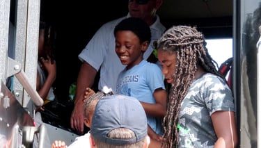 Boy smiling on firetruck at Reach Two event Brittany Woods