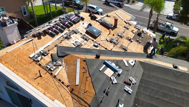Aerial view of roofing contractors installing new asphalt shingles and underlayment on a residential home roof.