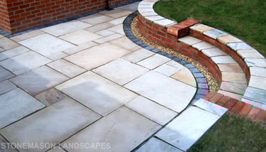 Multi-level sunken sandstone patio step up to lawn with retaining wall