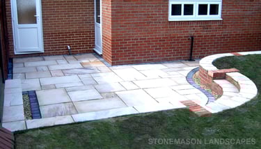 Multi-level sunken sandstone patio step up to lawn with retaining wall
