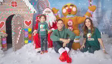 a family posing for a photo in front of a gingerbread house