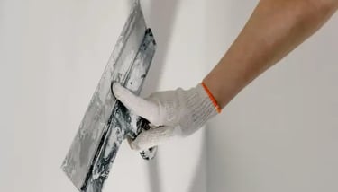 préparation des surfaces : un peintre tenant un couteau ratisse un mur avec une truelle