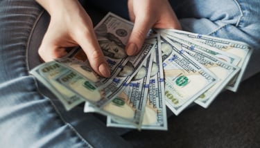person holding a wad of 100 dollar bills in their hand