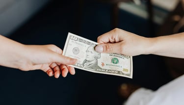 two people holding onto a dollar bill representing blog post about gold ira fees and a guide to understanding gold ira fees