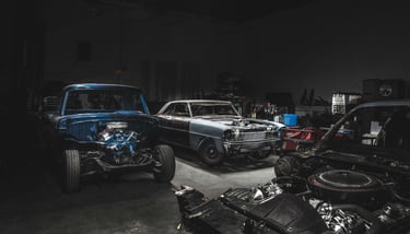 Classic vintage cars undergoing engine restoration in a professional automotive repair shop.