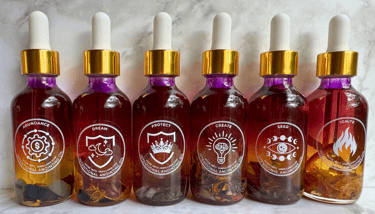 A row of beautiful fuschia to clear essential oil bottles with a gold screw on lid filled with herbs