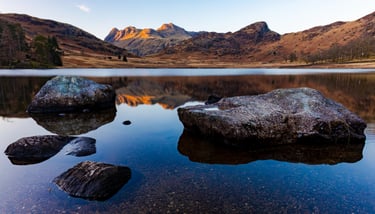 Scenic view of Blea Tarn in the Lake District with Langdale Pikes reflected in still water.