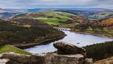 Scenic view of Ladybower Reservoir in the Peak District with stone bridge and autumn hills.