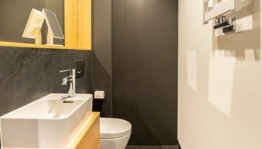 Nowoczesna łazienka: umywalka na drewnianej szafce, toaleta, czarne ściany