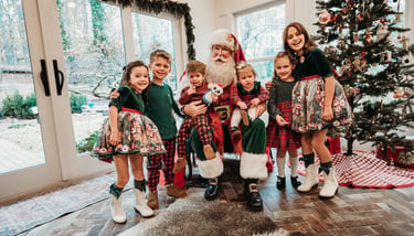 A group of happy children posing with Santa Claus next to a decorated Christmas tree for holiday photos.