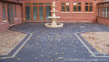 Charcoal standard block paving large patio and glass wall.