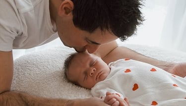 a man kissing a baby in a bed