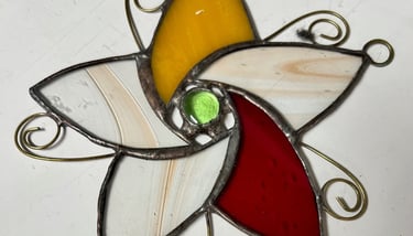 Stained glass flower with petals of amber, scarlet, and ivory made by Rochard MacDonald