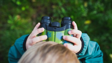 A child looking through binoculars while exploring outside