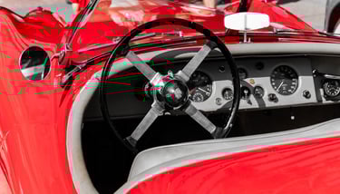 a red Jaguar with a steering wheel and dashboard