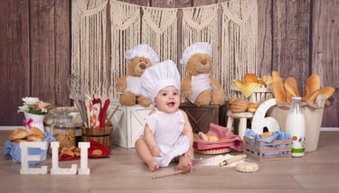 a baby in a chef hat and a teddy bear