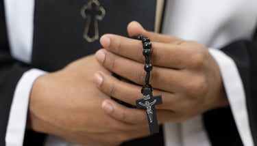 padre com rosário durante cerimónia fúnebre