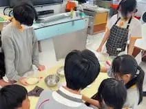 導師於學校課堂中教授中學生製作麵包，桌上展示發酵中麵糰和用具