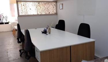 Espacio de trabajo en Red de Llaves con escritorios individuales, silla blanca y luz natural tenue.