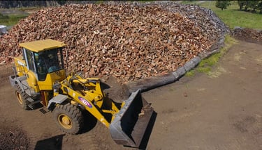 Loader in front of seasoned firewood