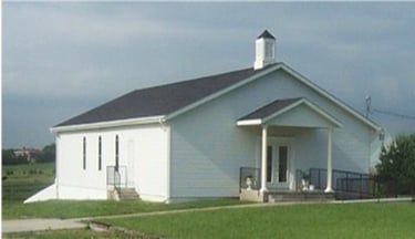 Basehor Church of Christ is a white church building with a black roof that has a covered porch.