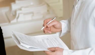 un hombre con bata blanca sosteniendo un bolígrafo y unos documentos clínicos
