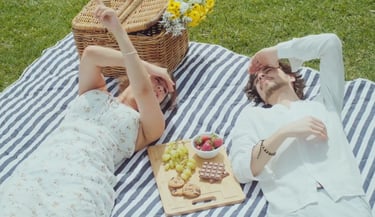 a man and woman laying on a blanket in a picnic blanket