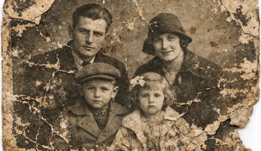 A damaged vintage family portrait showing a mother, father, and two children in early 20th-century attire.
