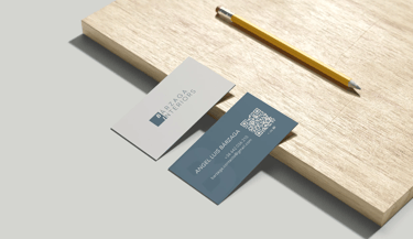 Tarjetas de presentación de Bárzaga Interiors al borde de una tabla y al lado de un lápiz.
