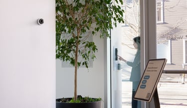 Visitor using Verkada intercom system at secure building entrance, monitored by indoor surveillance camera