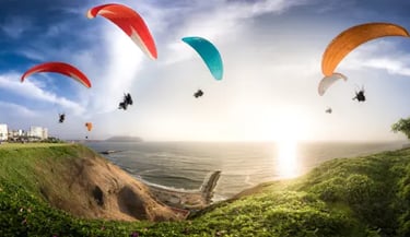 Paragliders flying over the Miraflores cliffs and Pacific Ocean in Lima, Peru during a bright sunset.