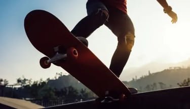 Low angle view of a person performing a skateboard trick at a skate park during a golden hour sunset.